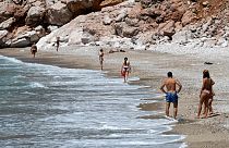 People walk on a beach near the town of Budva, on the Adriatic coast of Montenegro, on May 13, 2020.