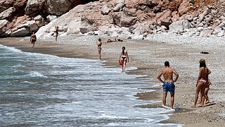 People walk on a beach near the town of Budva, on the Adriatic coast of Montenegro, on May 13, 2020.