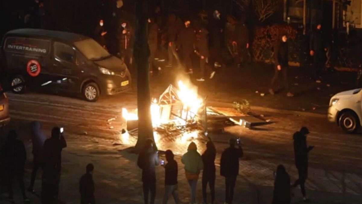 In this grab taken from video on Monday, Jan, 25, 2021, people use their phones to film items burning on a fire started by rioters, in Haarlem, Netherlands. 