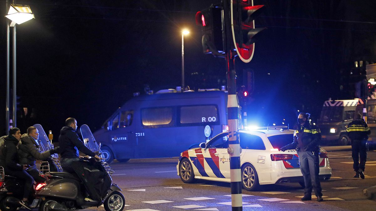 A police officers speaks to youths on scooters at a road block during a nation-wide curfew in Amsterdam, Netherlands, Tuesday, Jan. 26, 2021.