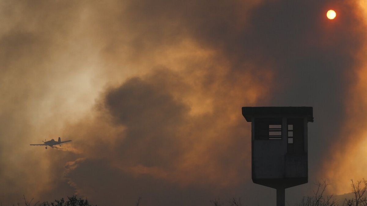 Egy tavalyi erdőtűz füstje Argentínában, a háttérben egy tűzoltó-repülőgéppel