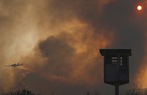 Egy tavalyi erdőtűz füstje Argentínában, a háttérben egy tűzoltó-repülőgéppel