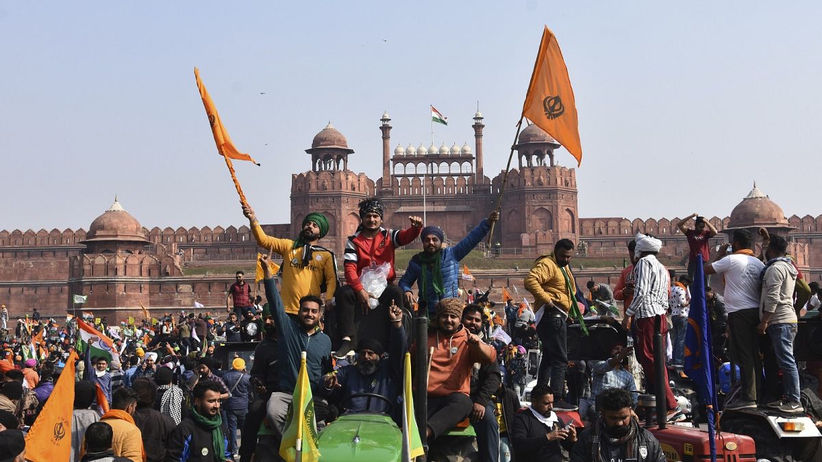 Sikhs wave the Nishan Sahib, a Sikh religious flag, as they arrive at the historic Red Fort monument in New Delhi, India, Tuesday, Jan. 26, 2021.