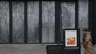 Una viandante mira la carta de un restaurante cerrado en Lonndres, Reino Unido