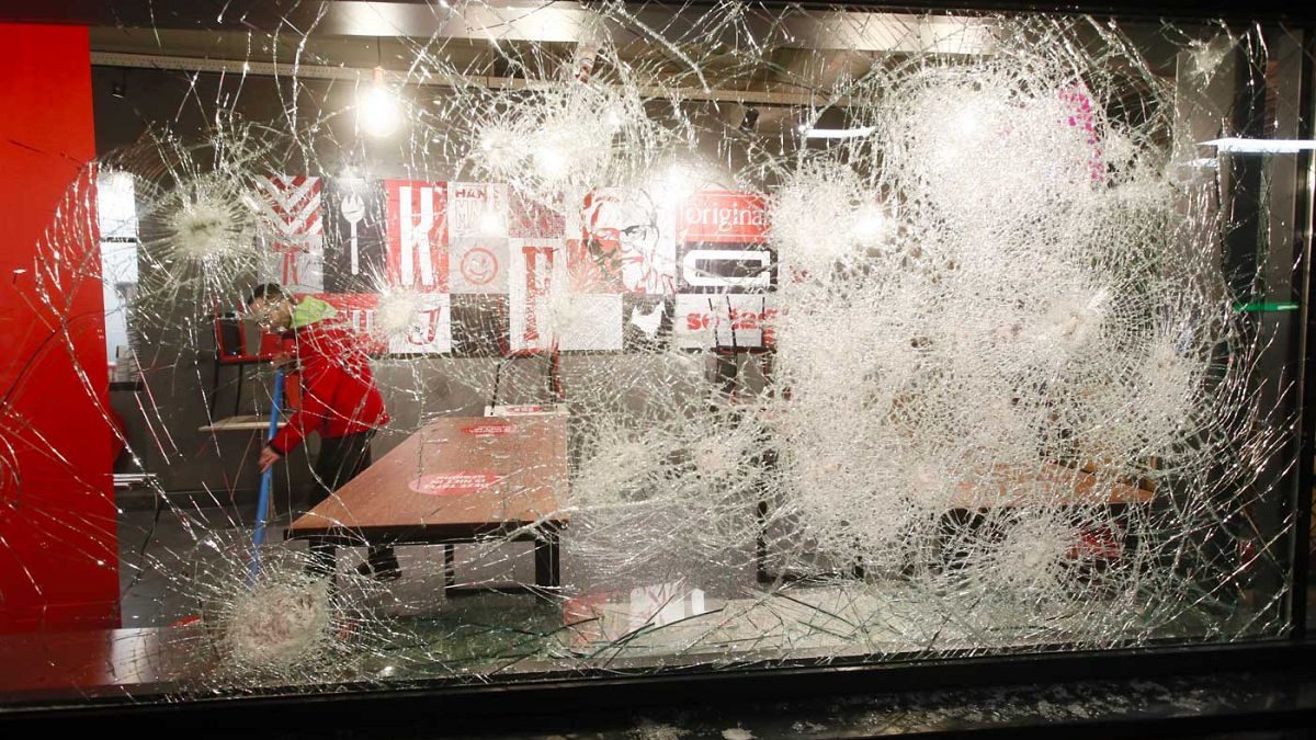 La vetrina di un fast-food a Rotterdam devastata dalle proteste