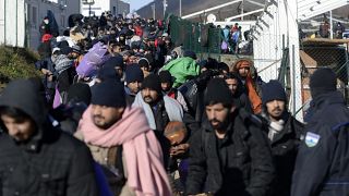 Police officers stand by migrants as they leave to be relocated from the Lipa camp northwestern Bosnia, near the border with Croatia, Bosnia, Tuesday, Dec. 29, 2020. 