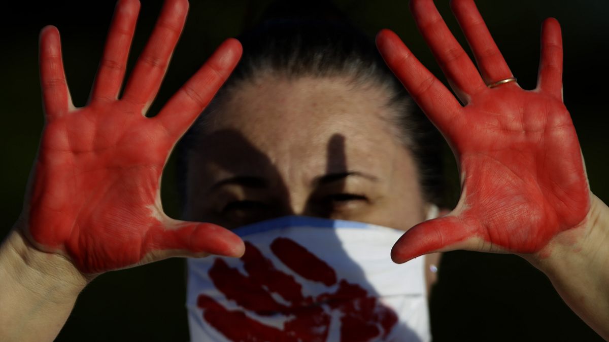 متظاهرة تظهر يديها المطلية باللون الأحمر والتي تمثل دماء أكثر من 200000 حالة وفاة بسبب كورونا في البرازيل 
