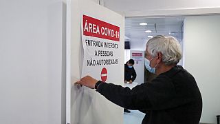 Un trabajador coloca un cartel a la entrada de un pasillo que conduce a las salas COVID-19 improvisadas en el Hospital Militar de Lisboa