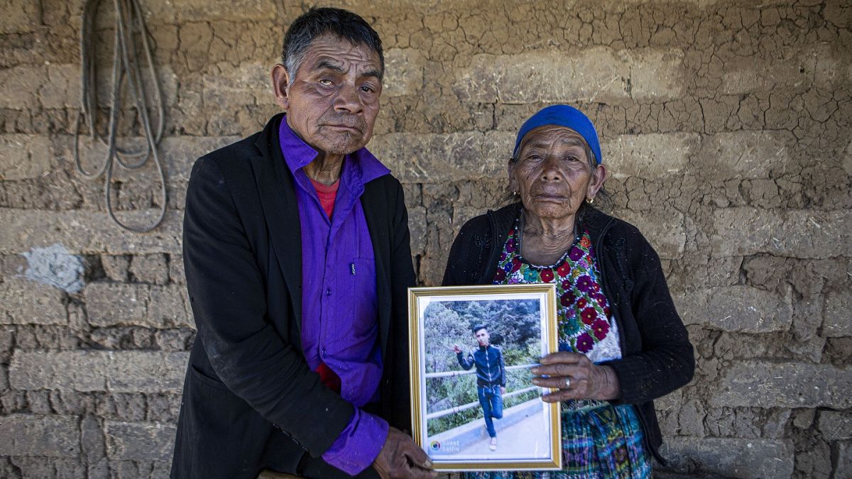 German y Maria Tomas posan para una fotografía sosteniendo un retrato enmarcado de su nieto Ivan Gudiel, en su casa en Comitancillo, Guatemala, el 27 de enero de 2021.