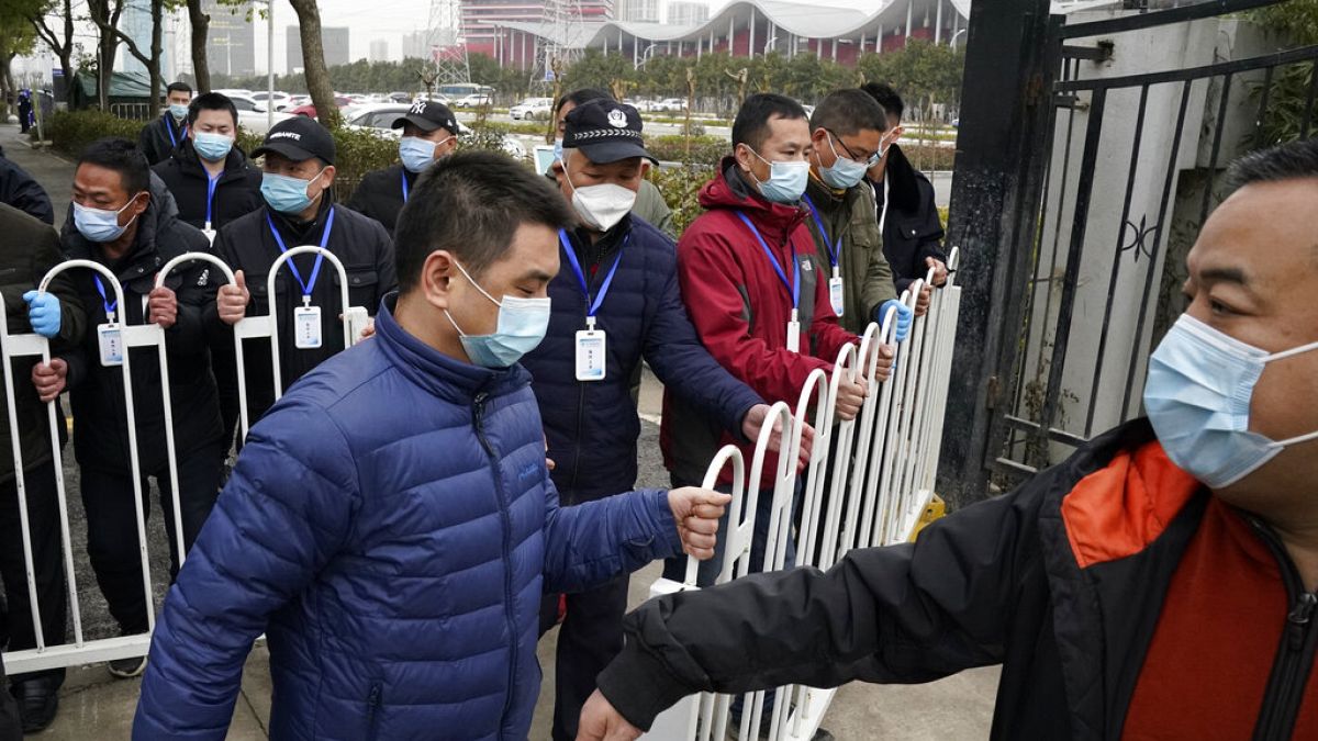 Security personnel move a barrier to clear the way for the World Health Organization team as they depart from the Wuhan Jinyintan Hospital after a field visit in Wuhan