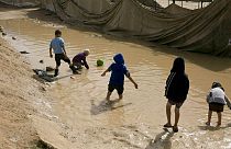 In this March 31, 2019 file photo, children play in a mud puddle in the section for foreign families at Al-Hol camp in Hasakeh province, Syria.