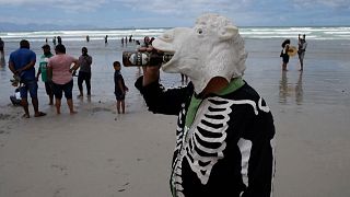 Man wearing a sheep face mask drinking a beer