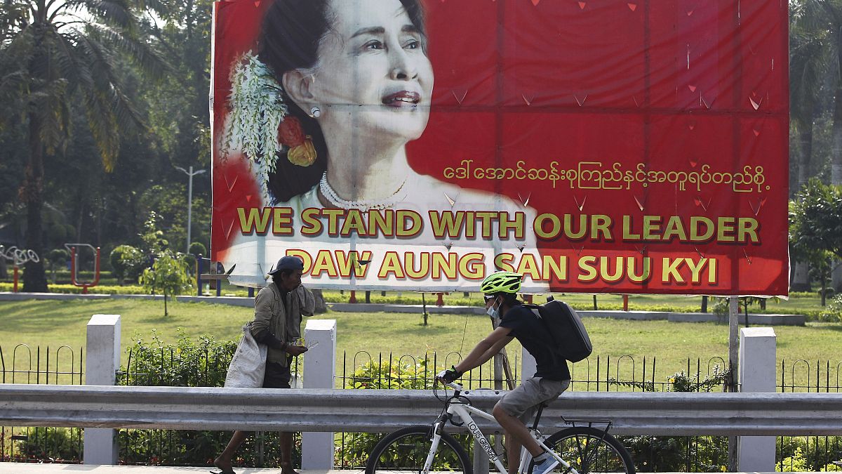 راكب دراجة هوائية، يمر عبر لافتة عليها صورة زعيمة ميانمار في يانغون، ميانمار.