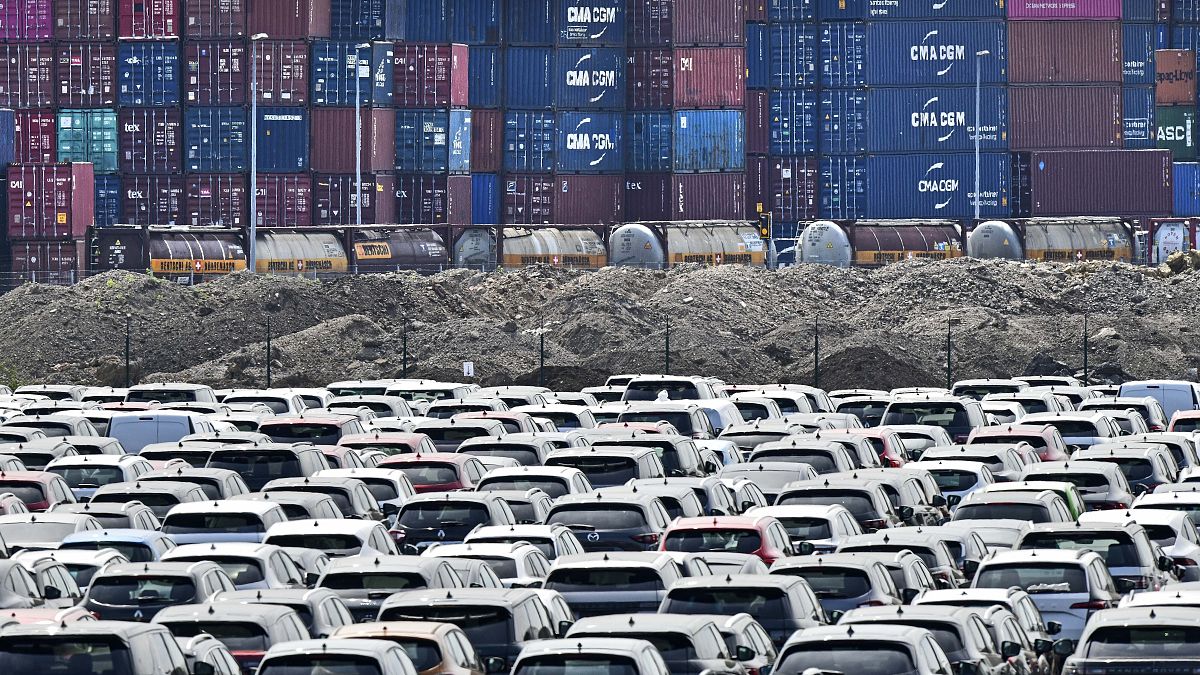 New cars are stored in front of containers at the 'logport' (logistic port) in Duisburg, Germany. Flle photo, Wednesday June 3, 2020.