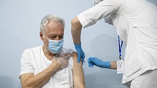 A Russian medical worker, right, administers a shot of Russia's Sputnik V coronavirus vaccine to a patient in a vaccination center in Moscow
