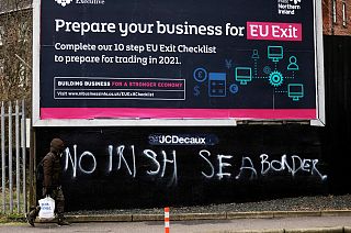 A man walks past graffiti reading "No Irish sea border" in the mainly loyalist Donegal road area of South Belfast, Northern Ireland, Saturday, Jan. 30, 2021.