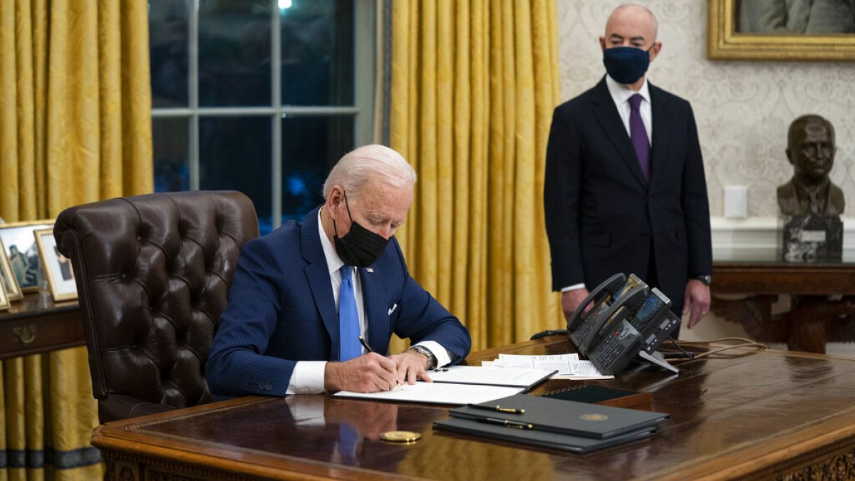 الرئيس الأمريكي جو بايدن يوقع على مراسيم متعلقة بالهجرة  فيما يقف إلى جانبه وزير الأمن الداخلي  أليخاندرو مايوركاس