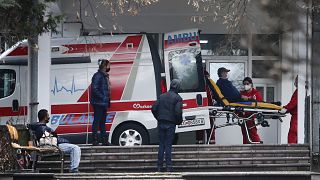 In this picture taken on Tuesday, Dec. 29, 2020, health workers wheel out a patient from an ambulance, at the entrance of the University Clinic complex in Skopje, North Macedo