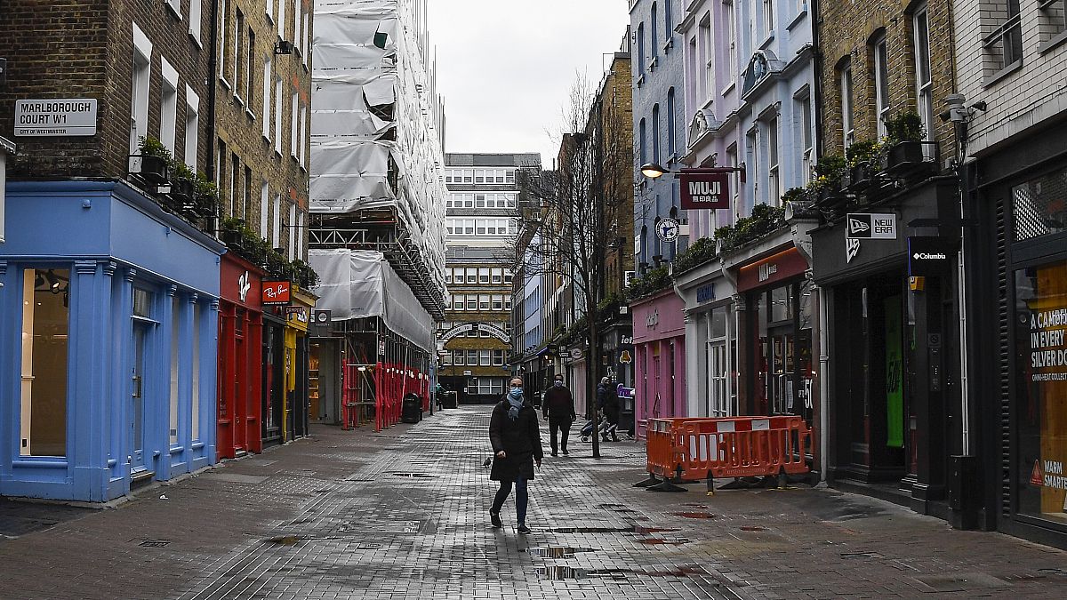 A woman wears a face mask as she walks in a deserted Carnaby Street, in London, Wednesday, Feb. 3, 2021.