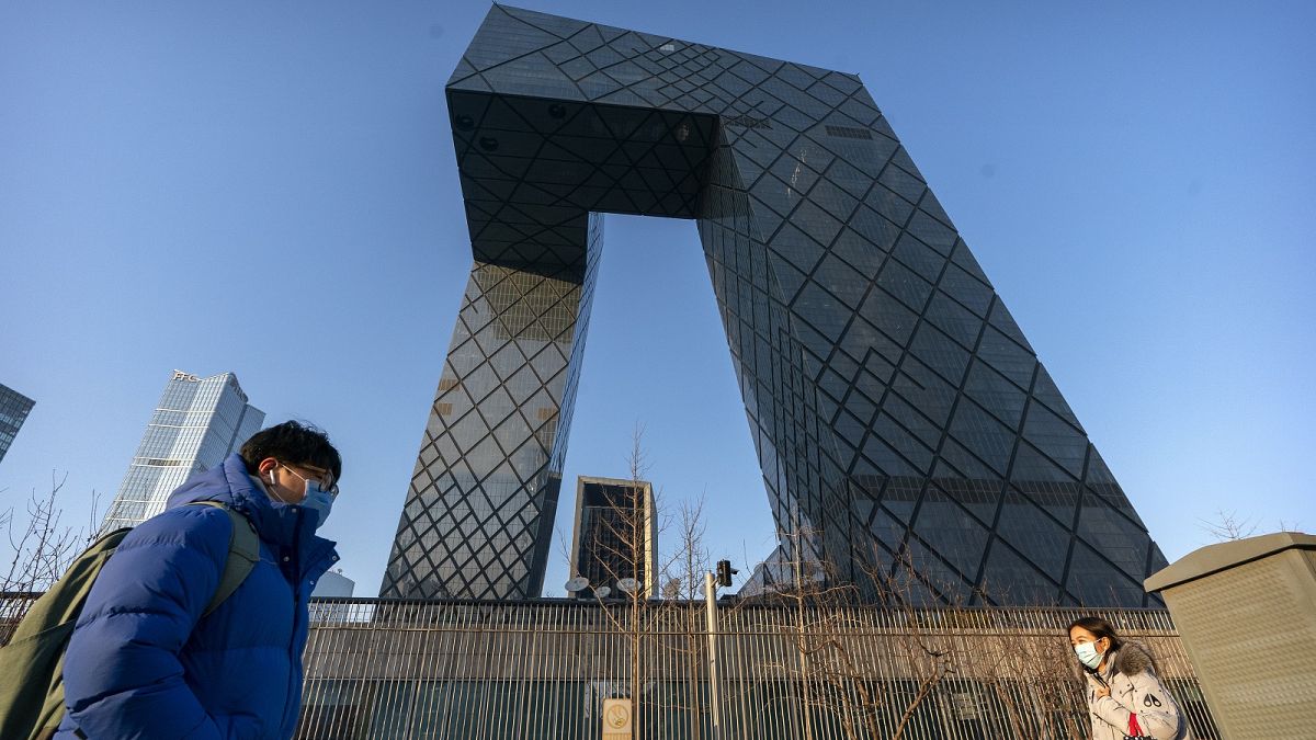 People walk past the CCTV Headquarters building, the home of Chinese state-run television network CCTV and its overseas arm CGTN, in Beijing on Feb. 4, 2021.