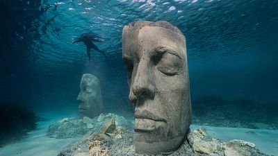 The mask-like sculptures sit on the seabed just not far from the shore. The mask-like sculptures sit on the seabed just not far from the shore.