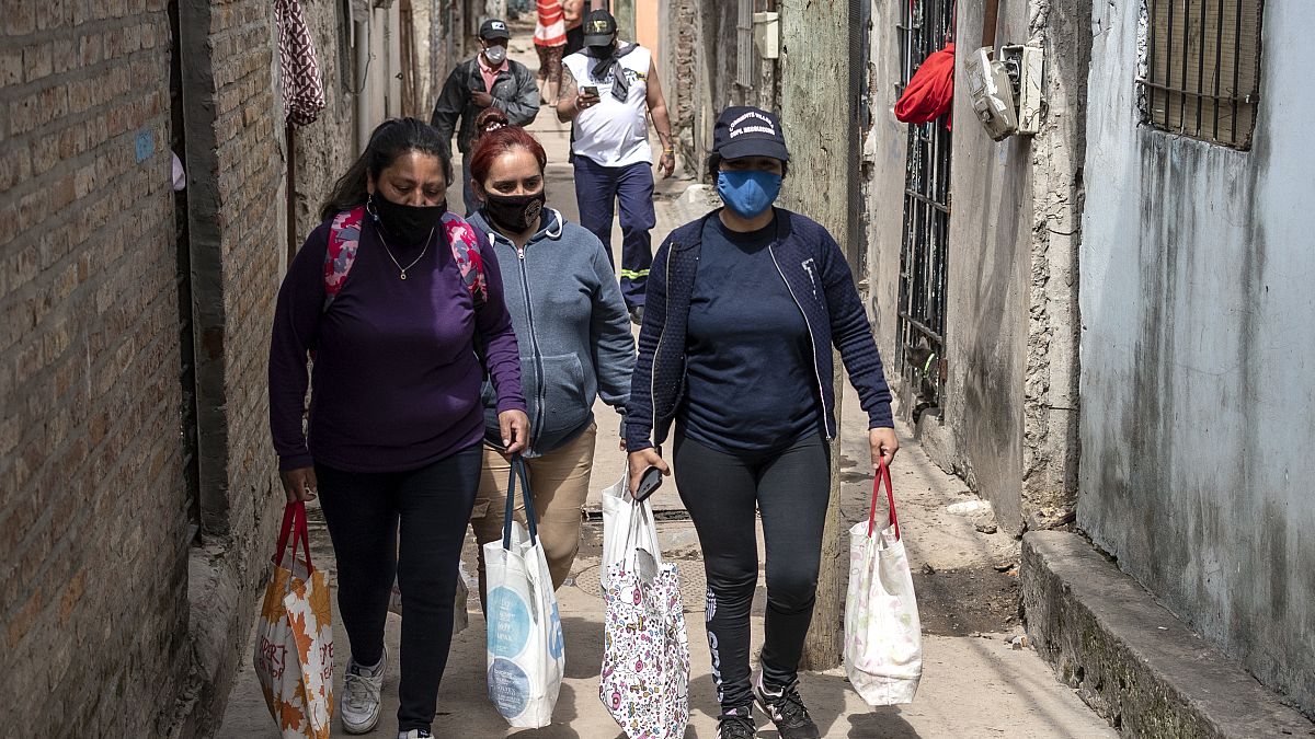 Unas mujeres llevan bolsas con raciones de comida de un comedor social para alimentar a las personas más afectadas por la crisis económica.
