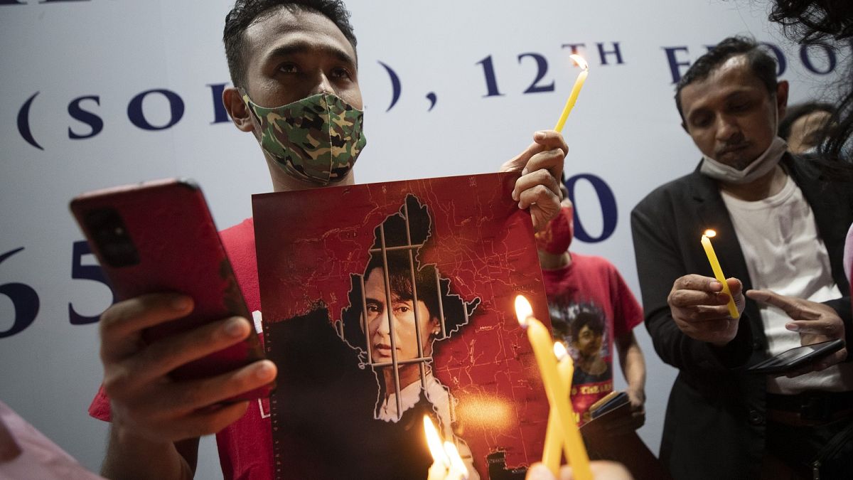 Myanmar nationals in Thailand hold pictures of Aung San Suu Kyi and lit candles during a protest in front of the Myanmar Embassy in Bangkok, Feb. 4, 2021.