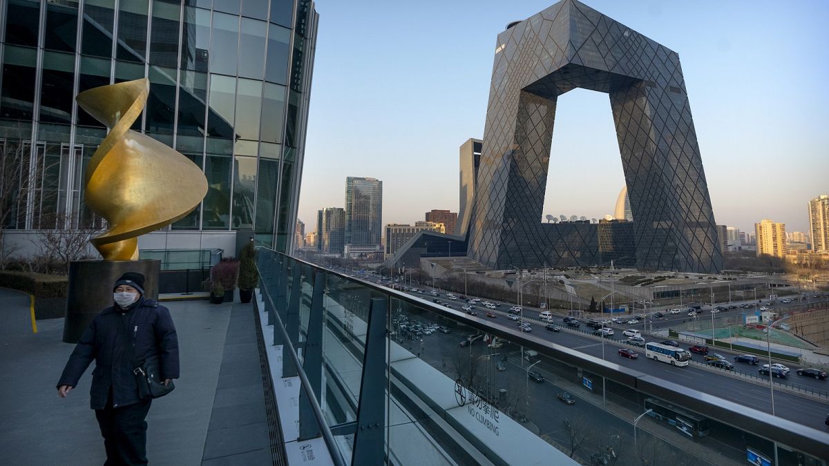 A man walks along an observation deck near the CCTV Headquarters building, the home of Chinese state-run television network CCTV and its overseas arm CGTN, in Beijing.