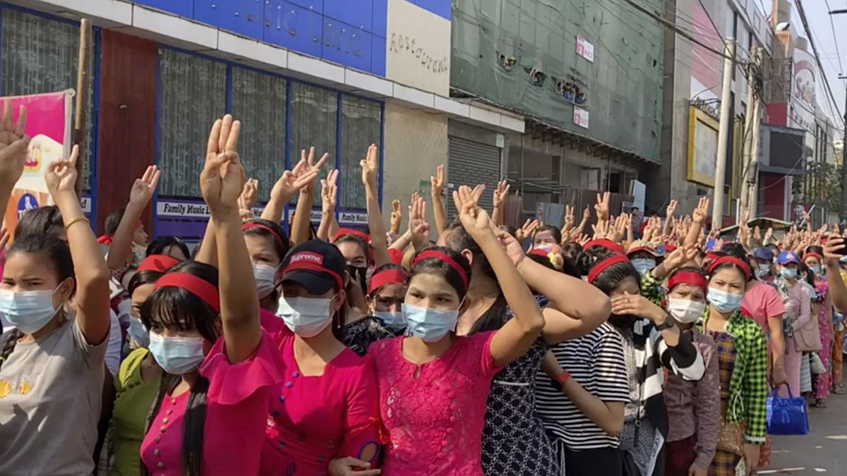 In this image made from video, protesters flash the three-fingered salute while they gather to march Saturday, Feb. 6, 2021, in Yangon, Myanmar.