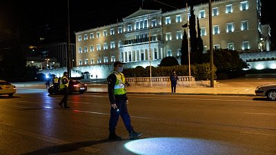 Policeman at checkpoint where drivers are asked to present their movement permits, in Athens, Saturday, Feb. 6, 2021