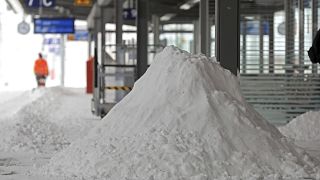 A Deutsche Bahn employee clears snow on a platform at the main station in Magdeburg, Germany, Sunday, Feb. 7, 2021. (Peter Gercke/dpa via AP)