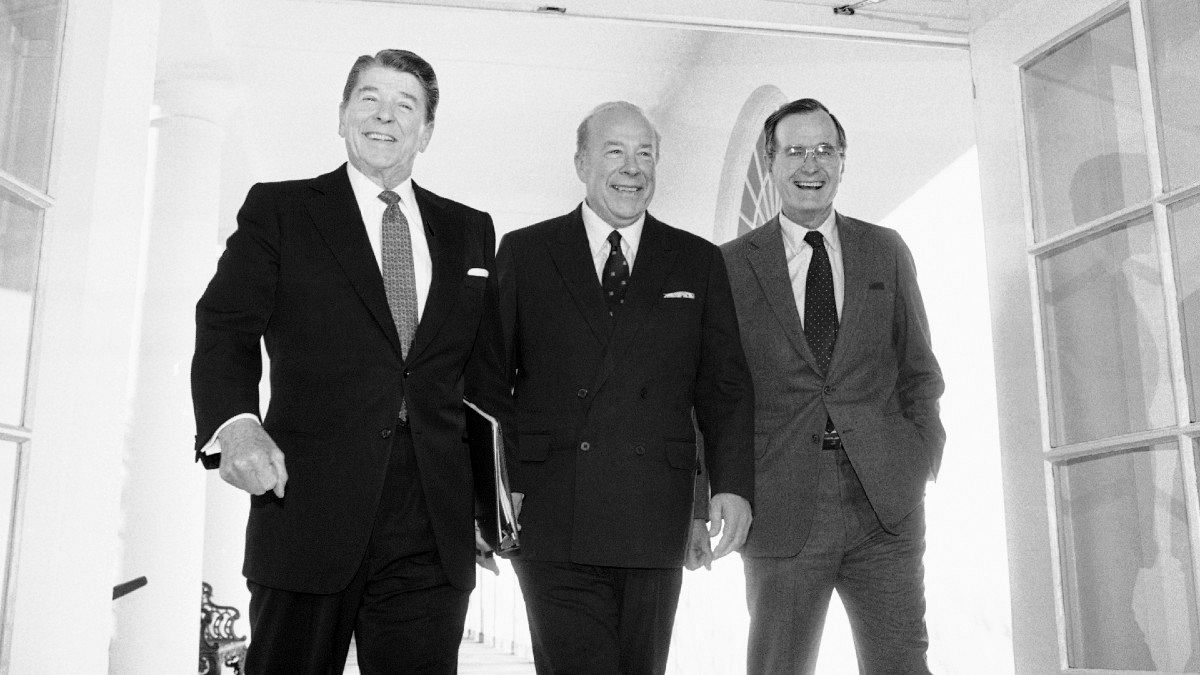 جرج شولتز وزیر خارجه وقت بین جرج بوش پدر، معاون رئيس جمهوری وقت (سمت راست) و رونالد ریگان، رئيس جمهوری وقت (سمت چپ) ایستاده است