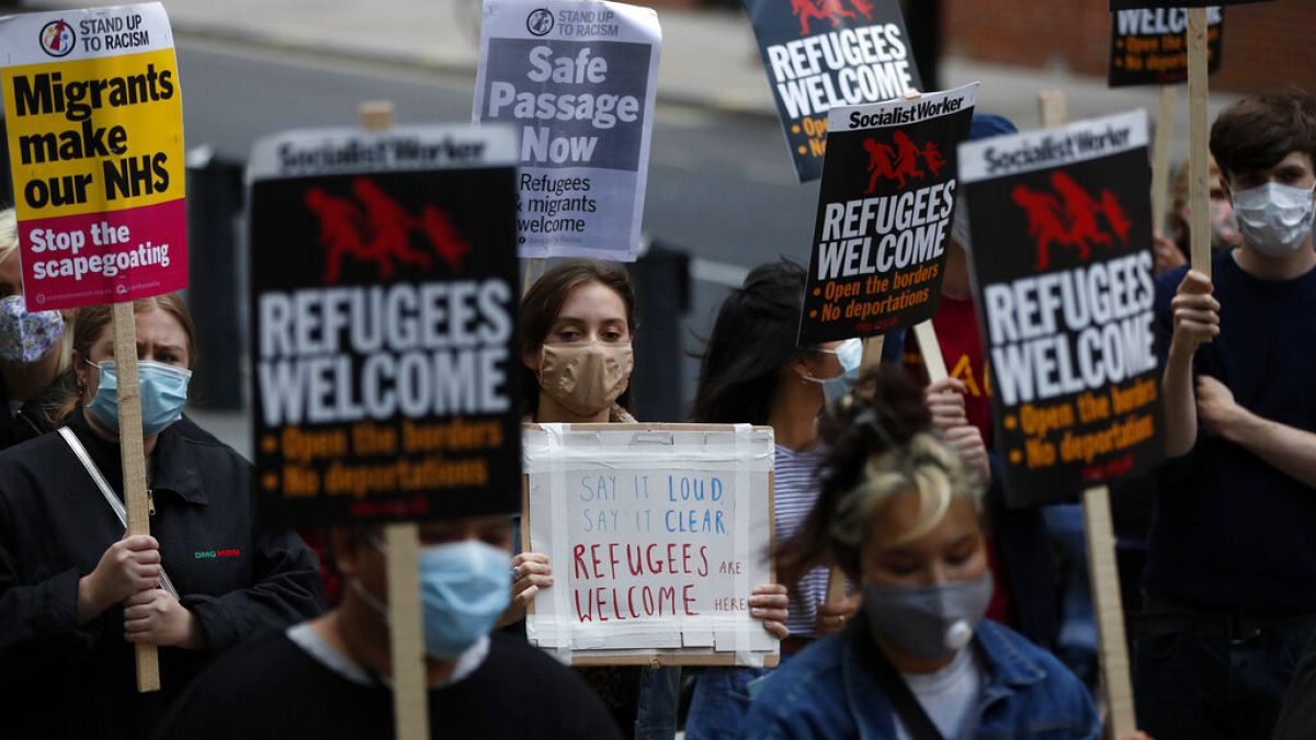 Protestors hold placards during a pro-migrants protest outside the government's Home Office in London, Tuesday, Aug. 25, 2020