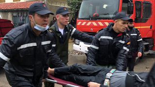 Emergency services carry a man on a stretcher at the site of illegal underground textile workshop that flooded after heavy rain fall in Morocco's city of Tangiers on February 