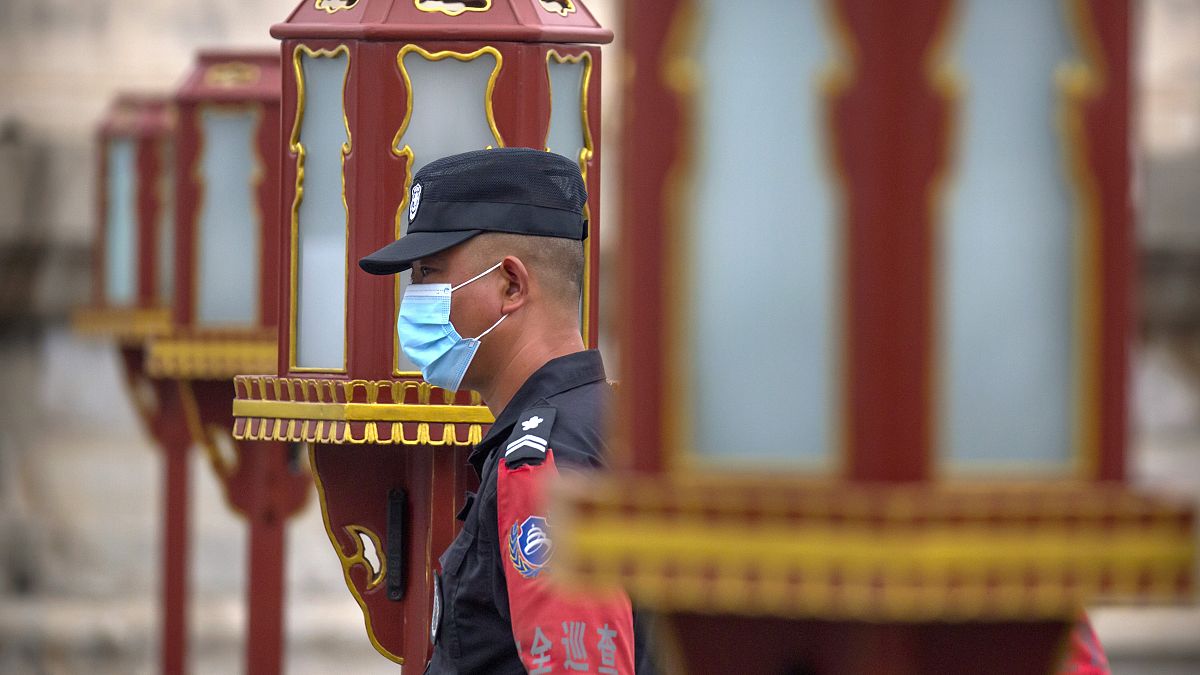 ضابط أمن يرتدي كمامة أمام معبد السماء في بكين، الصين.