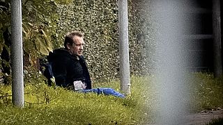 Images from the escape showed Peter Madsen sitting on the grass against a fence with his hands behind his back as police aimed guns at him from a distance.