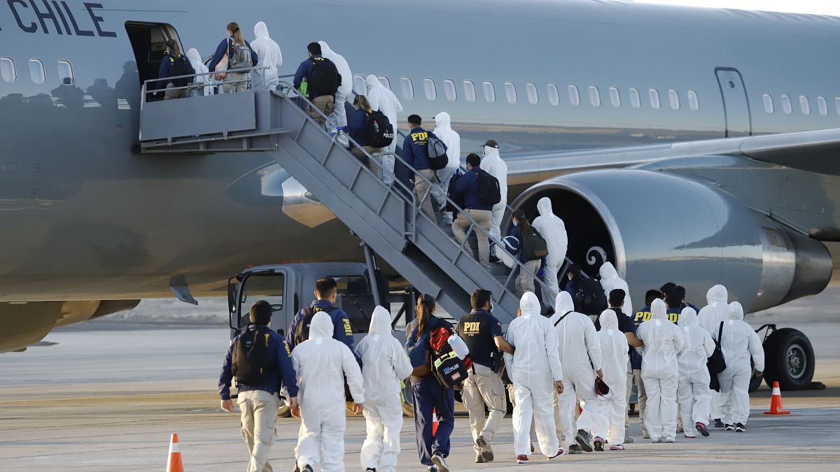 Un grupo de migrantes sube el avión del Ejército chileno en el que han sido deportados.