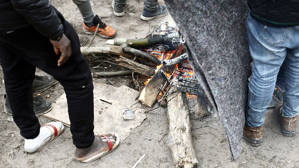 Des exilés se réchauffant au coin du feu dans un camp de fortune, à Calais, dans le nord de la France, le 31 janvier 2020.