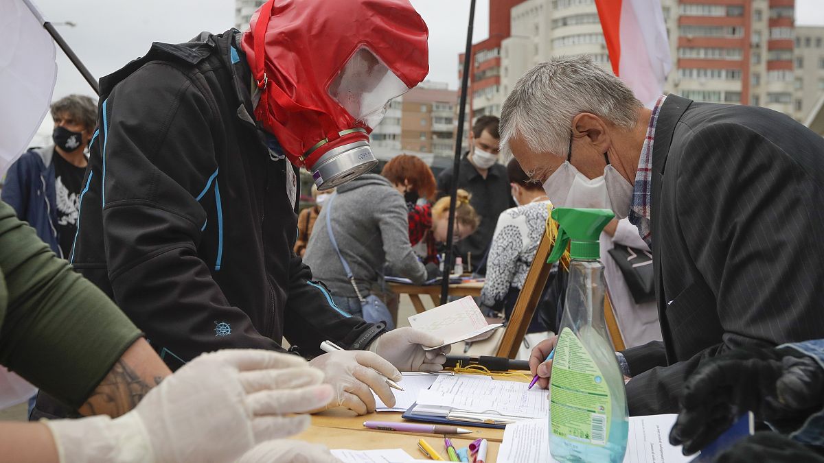 In this file June 14, 2020 photo, people, wearing face masks to protect against coronavirus, sign to support potential presidential candidates in Minsk, Belarus.