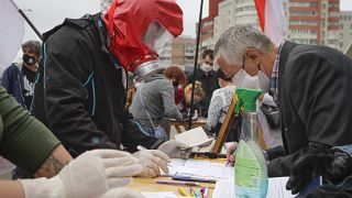 In this file June 14, 2020 photo, people, wearing face masks to protect against coronavirus, sign to support potential presidential candidates in Minsk, Belarus.