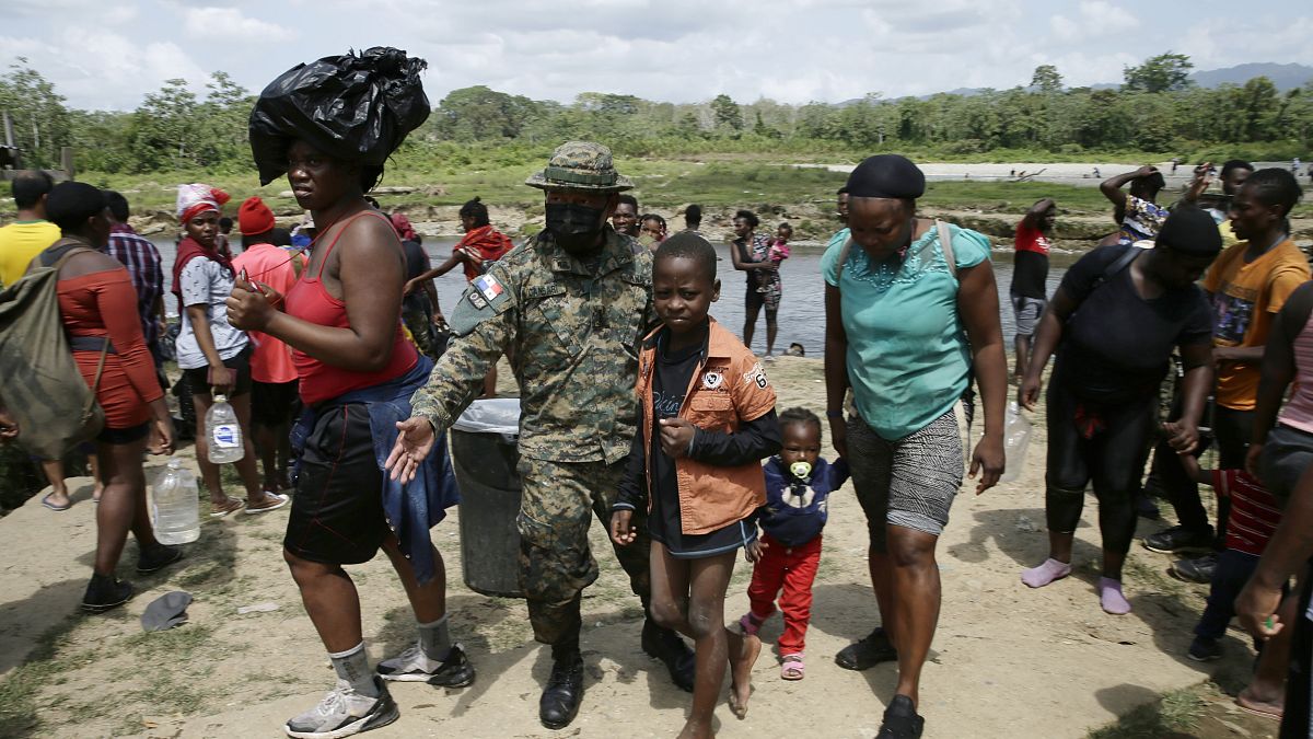 Migrantes son recibidos por un oficial de la policía fronteriza panameño en la localidad de Bajo Chiquito en Darién, Panamá, el 10 de febrero de 2021.
