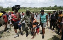 Migrantes son recibidos por un oficial de la policía fronteriza panameño en la localidad de Bajo Chiquito en Darién, Panamá, el 10 de febrero de 2021.