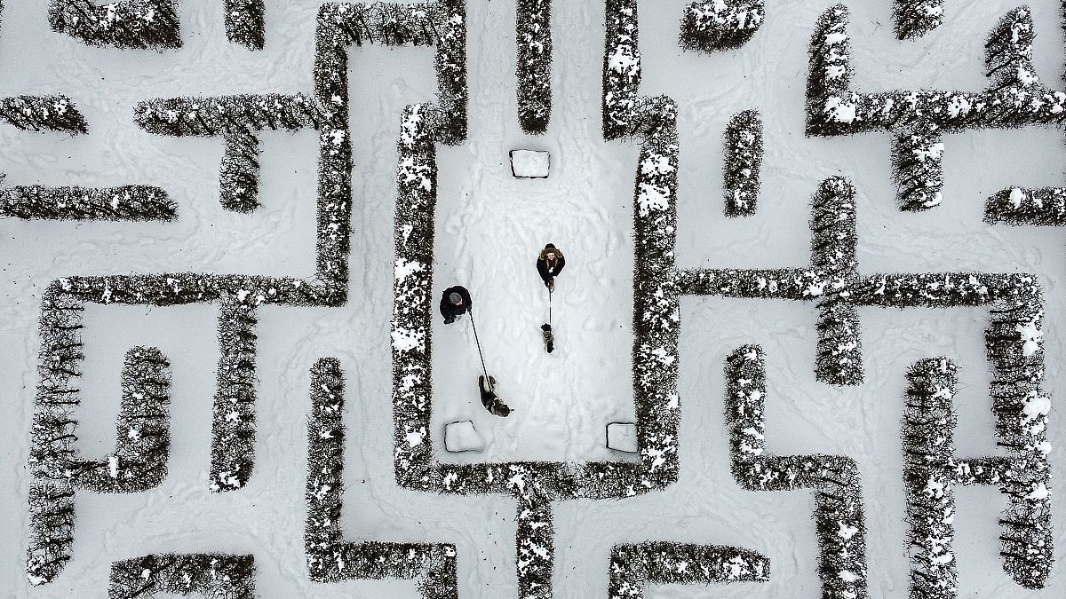 People walk with their dogs in a snow-covered garden maze in Gelsenkirchen, Germany. Extreme winter weather hit the north and west of the country. February 10, 2021