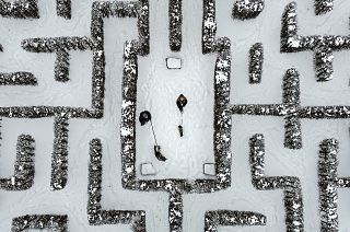 People walk with their dogs in a snow-covered garden maze in Gelsenkirchen, Germany. Extreme winter weather hit the north and west of the country. February 10, 2021