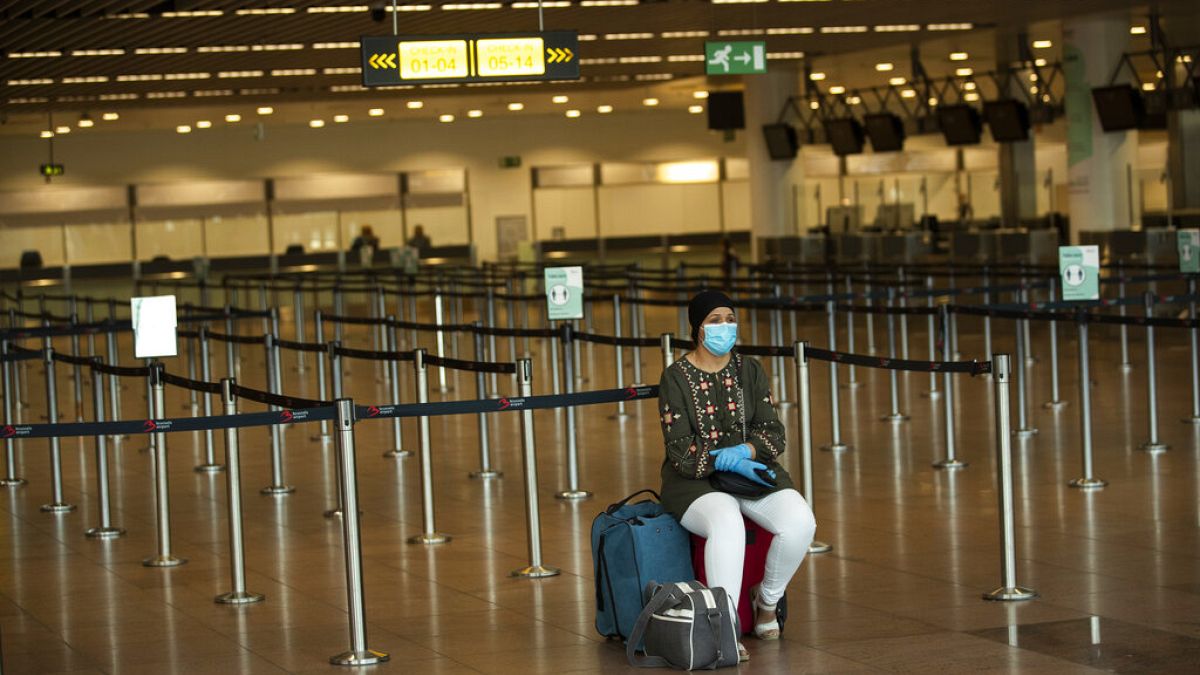 A passenger, wearing a face mask to protect against the spread of coronavirus, sits at the almost empty departures hall at the Zaventem international airport in Brussels,