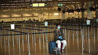 A passenger, wearing a face mask to protect against the spread of coronavirus, sits at the almost empty departures hall at the Zaventem international airport in Brussels,