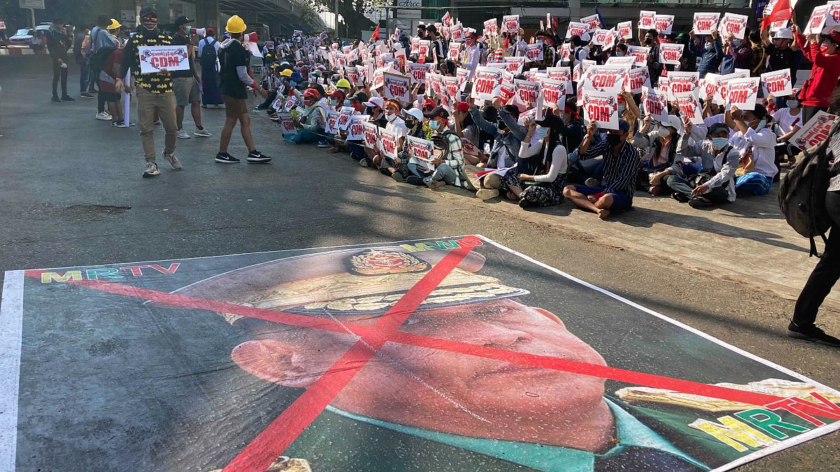 A large image that has an X mark on the face of Commander in chief Senior Gen. Min Aung Hlaing lies on a road as anti-coup protesters gather in Yangon, Sunday, Feb. 14, 2021.