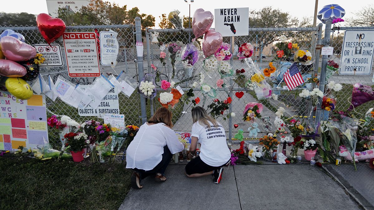 People light candles at a makeshift memorial outside a high school where 17 students and faculty were killed in a mass shooting in Parkland, Florida. Feb. 18, 2018