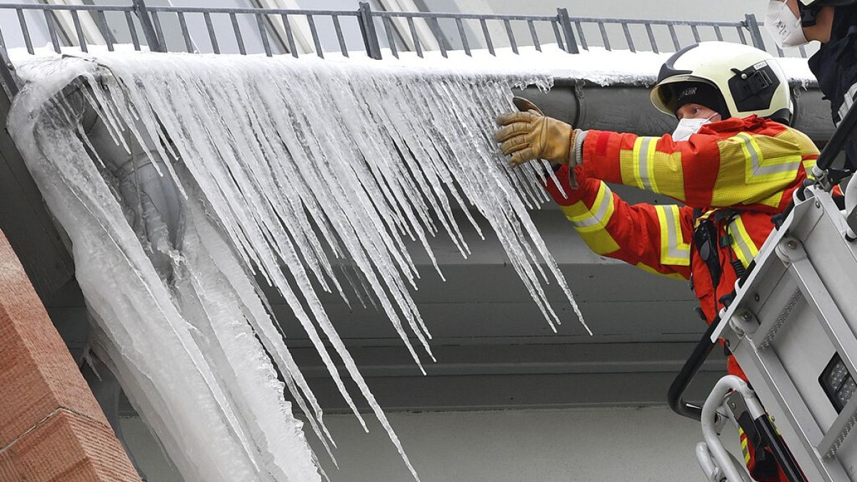 Feuerwehrleute brechen große Eiszapfen aus der Dachrinne eines Hauses in Erfurt, Deutschland, 11.02.2021