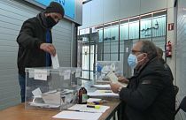A masked voter places his ballot in a polling station in Barcelona, Catalonia, Spain